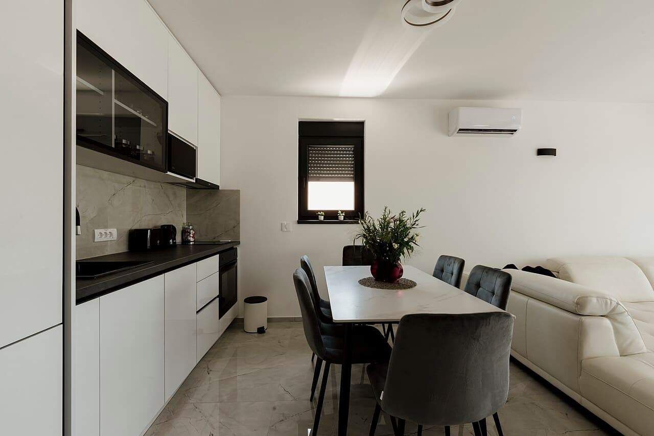 White kitchen cabinets with dark countertops beside a dining table and chairs