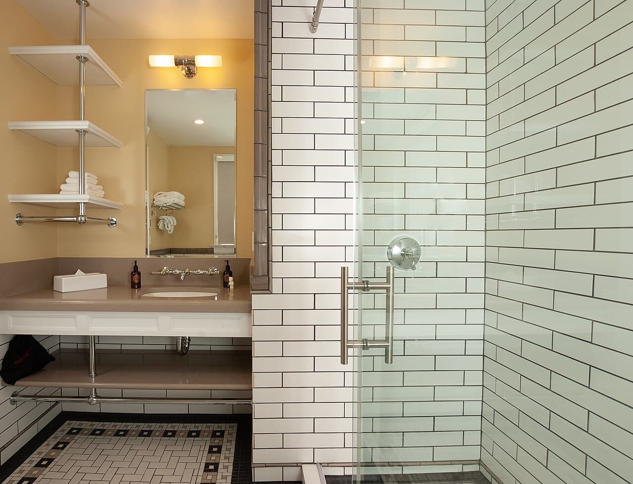 Bathroom with white subway-tile shower, glass door, sink vanity, mirror and open shelves